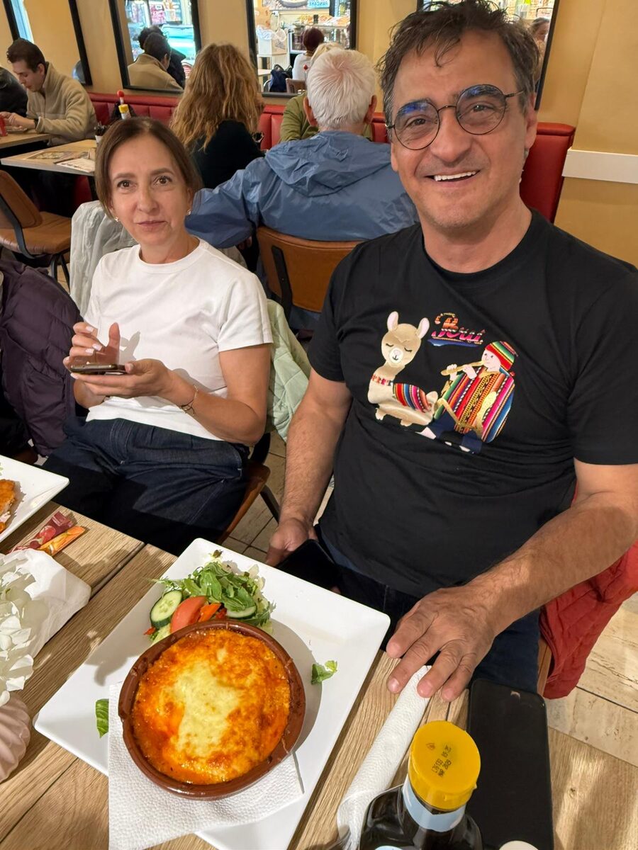 Twee gasten aan tafel, met een schaal lasagne en salade voor zich