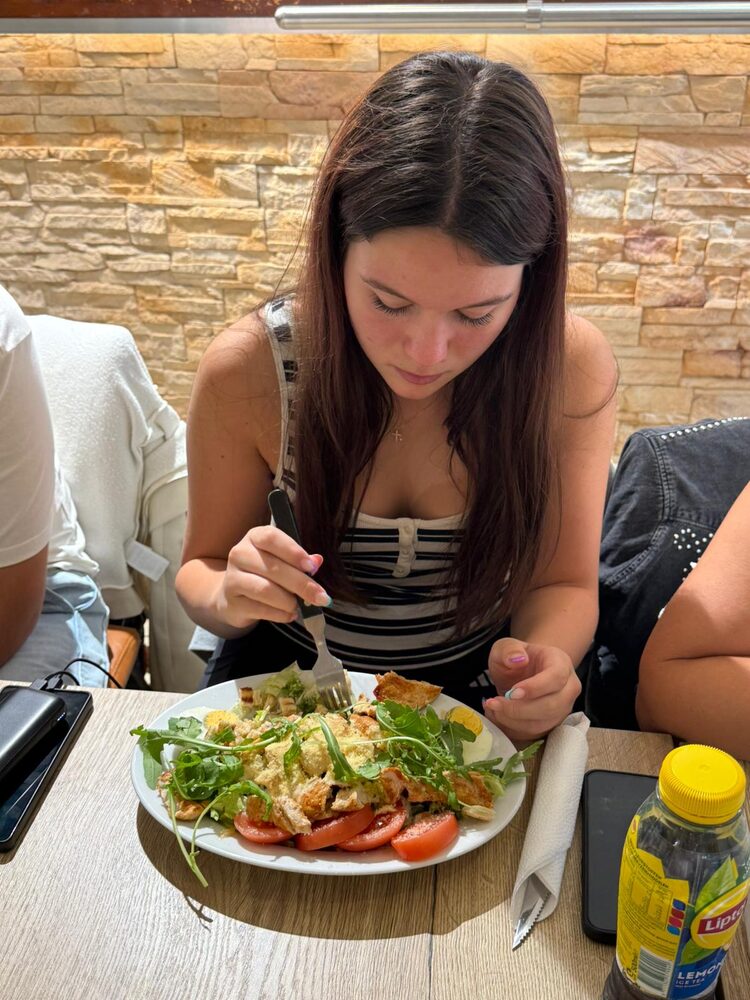 Een gast aan tafel met een kip caesar salade met tomaat en ei
