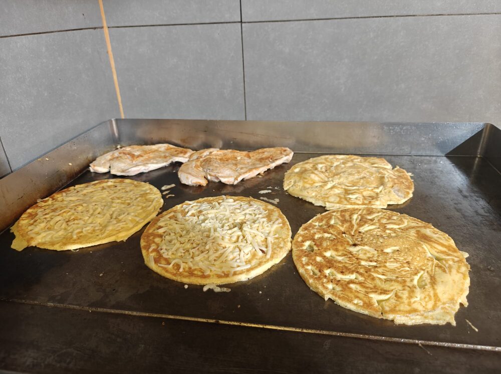 Pannenkoeken en kipfilet naast elkaar op de hete bakplaat