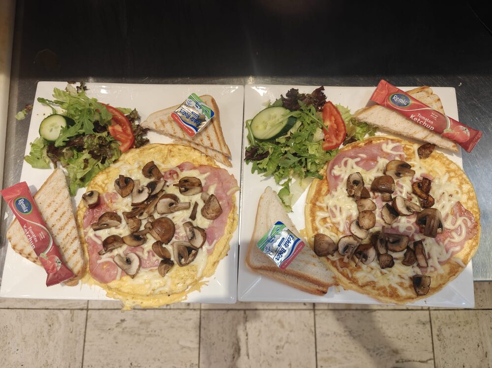 Twee uitsmijters met ham en champignons, met salade en getoast brood