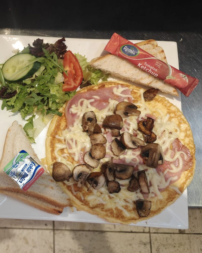 Een omelet met ham en champignons van dichtbij, met salade en toast