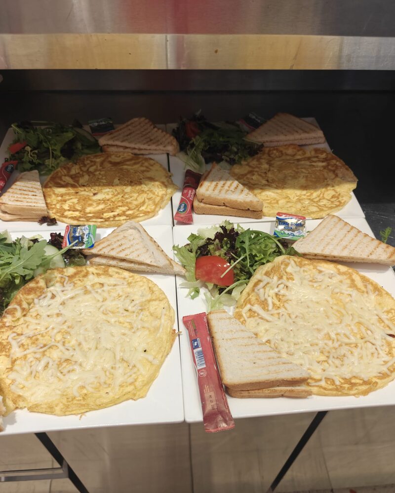Een kaasomelet met getoast brood en een kleine salade op een wit bord