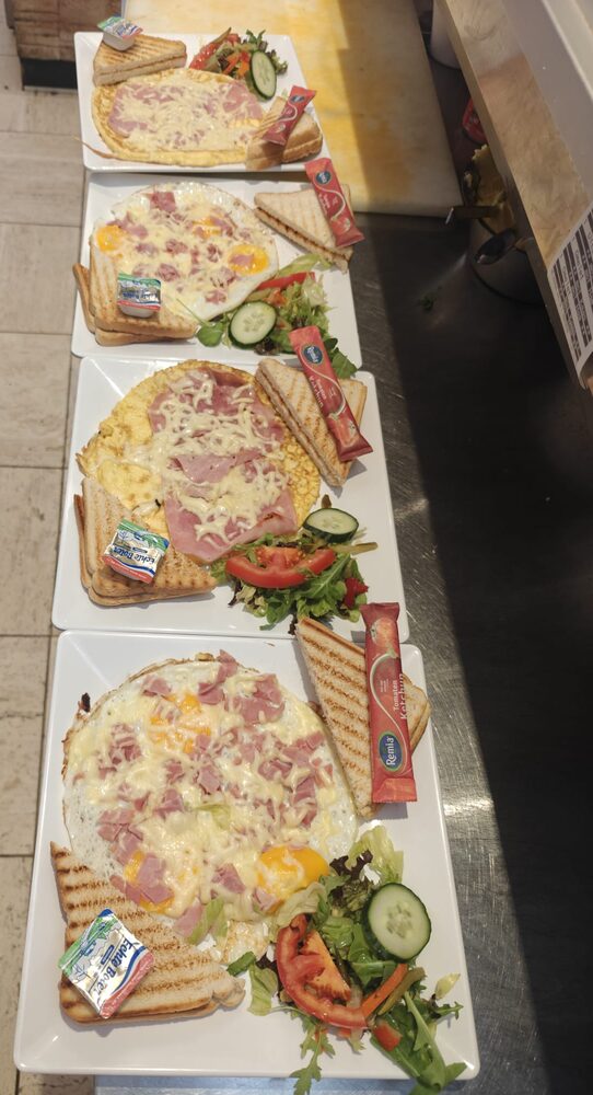 Vier borden met uitsmijter en toast op een rij op de toonbank, klaar om uit te serveren