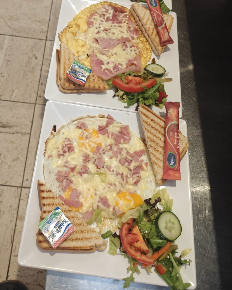 Twee borden uitsmijter met ham, geserveerd met getoast brood en salade