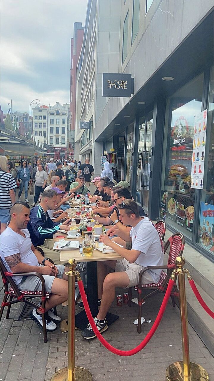 Gasten lunchen samen aan lange tafels op het terras van Amarylles