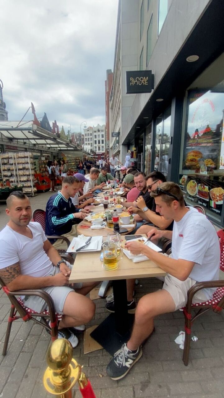 Vrienden ontbijten op het terras, met de bloemenmarkt aan de overkant